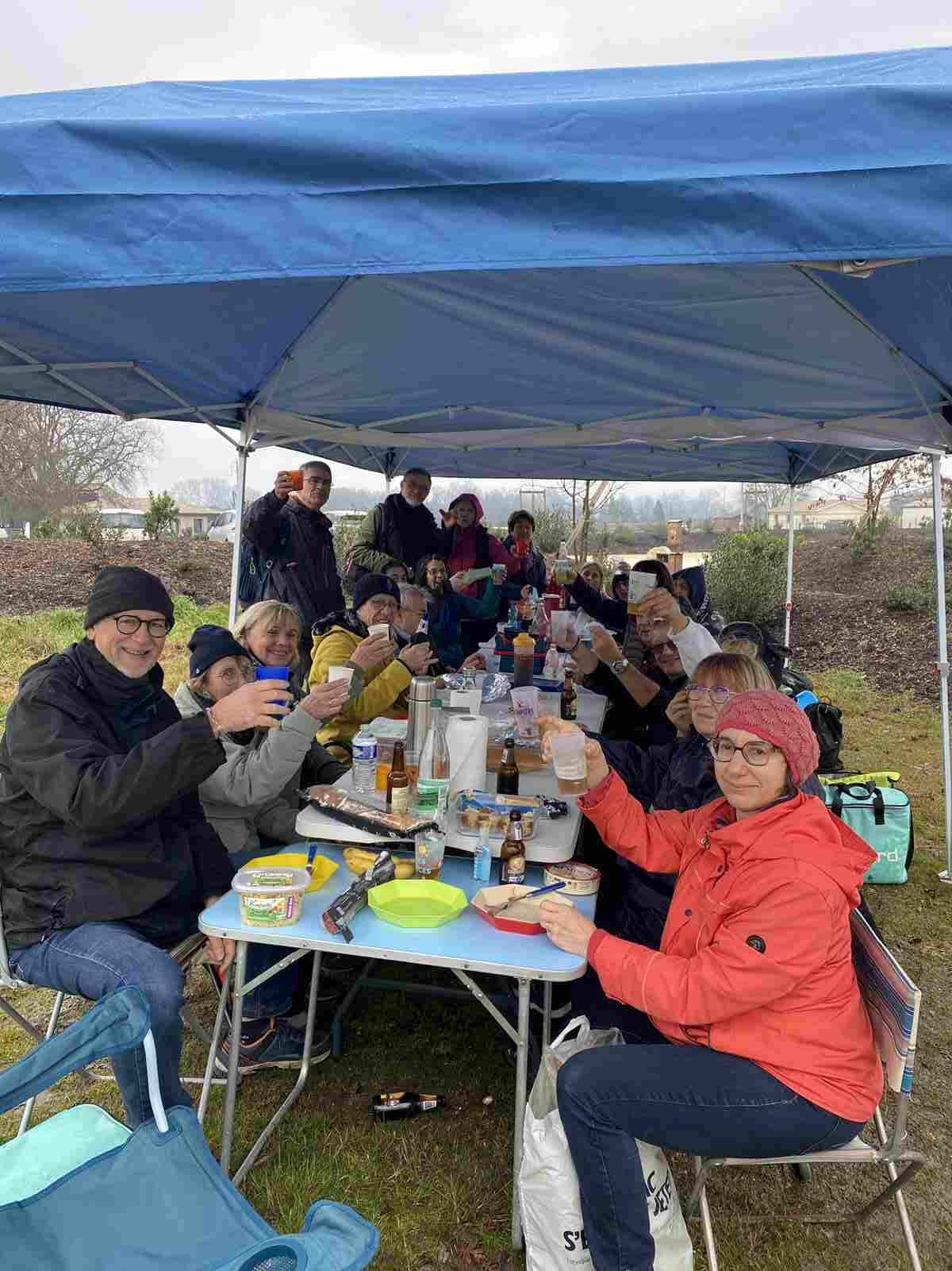 Photo des marcheurs assis à table, sous des barnums.
